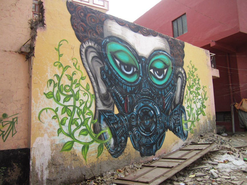 This mural of a Buddha-like face covered in a gas mask sprouting leaves, by artist Yantr, faces a heavily congested intersection in Khirki village. Used as a thoroughfare to get to a major shopping mall near the village, it is known for being a particularly polluted spot located between the urban and the semi-rural.