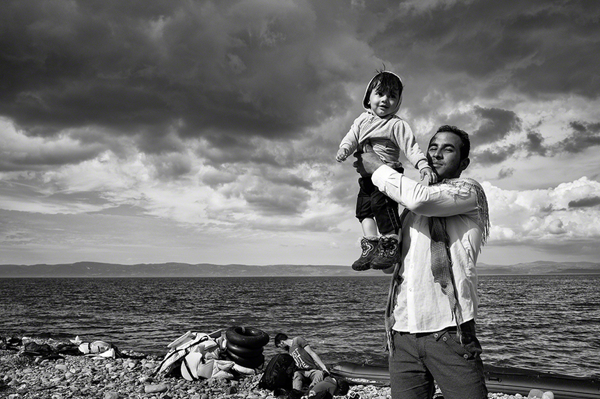 TOM STODDART, Lesbos, Greece, 2015: A father celebrates his family’s safe passage to Lesbos after a stormy crossing over the Aegean Sea from Turkey. Courtesy the artist and Annenberg Space for Photography, Los Angeles.