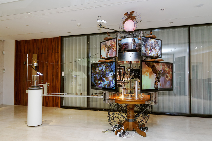 Installation view of JON KESSLER’s The World is Cuckoo (Clock), 2016, mixed media with lights, motor, video cameras, monitors and Panerai watch, 162.56 cm x 337.82 cm x 271.78 cm, at the 6th Guangzhou Triennial, “As We May Think: Feedforward,” Guangdong Museum of Art, 2018–19.