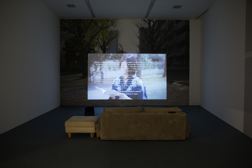 Partial installation view of KOKI TANAKA’s Vulnerable Histories (A Road Movie), 2018, film: 78 min, installation: three single-channel videos on monitor with color and sound; three single-channel video projections with color and sound; two-channel video on monitors with color, no sound; inkjet print on paper, UV-ink on craft paper, inkjet print on wallpaper, movable walls, second-hand sofas, carpet, at the Migros Museum of Contemporary Art, Zurich, 2018.