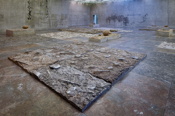 Among the participating artists at Dhaka Art Summit 2020 is ADRIÁN VILLAR ROJAS. Installation view of ADRIÁN VILLAR ROJAS’s  The Theater of Disappearance, 2017, floor tiles and blocks of brown marble with incrustations of ammonites and orthocer fossils, paintings and drawings on walls, and ivies and tinted artificial light on glass ceiling, dimensions variable, at “The Theater of Disappearance,” Kunsthaus Bregenz, 2017. Courtesy the artist and Kunsthaus Bregenz.