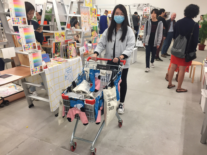 Tai Kwun Contemporary staff pushing carts of fair merchandise designed by CHARLENE MAN. Photo by HG Masters for ArtAsiaPacific.