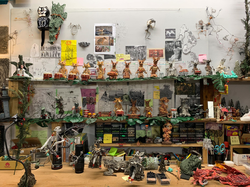 Musicians and other figures line the shelves of Zhang Xu’s studio. A 2019 calendar is on the wall alongside Zhang Xu’s reference images.